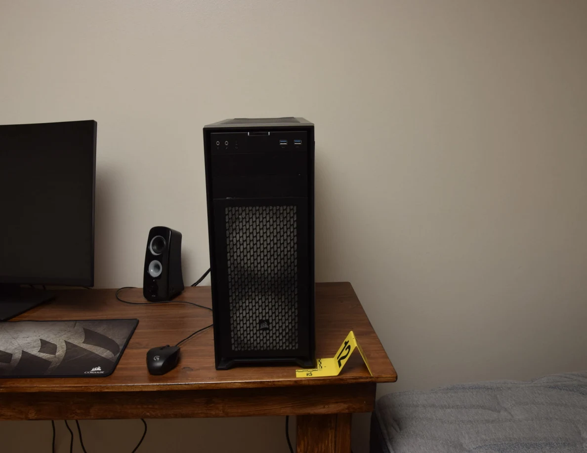 Computer tower on a wooden desk beside yellow marker 12.