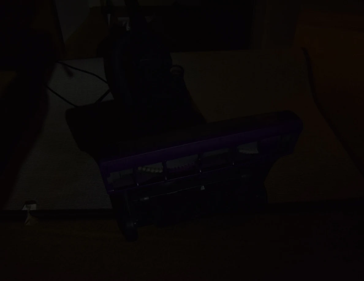 Very dark view of an overturned vacuum cleaner on a folded-back rug.