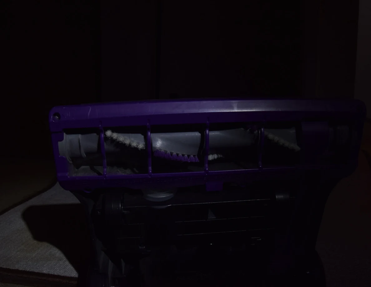 Dim close view of a purple vacuum base and brush roll.