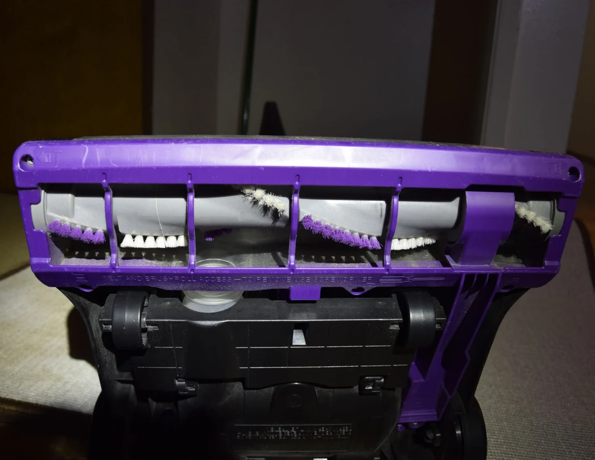 Close view of a vacuum brush roll with alternating white and purple bristles.