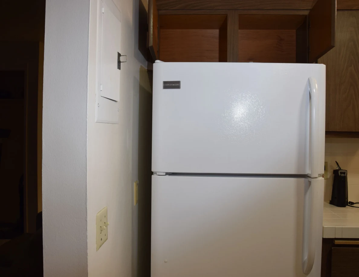 Upper refrigerator and empty open wooden cupboard above it.