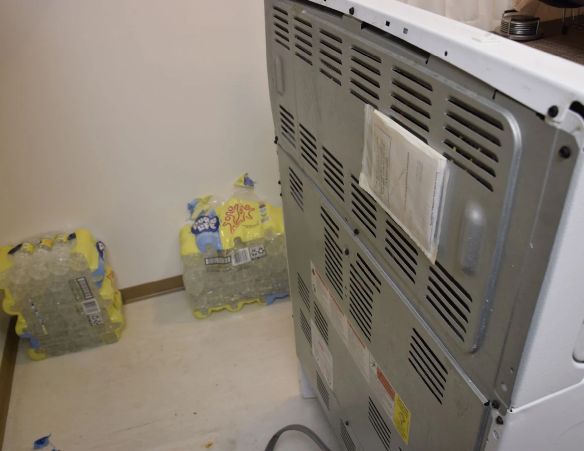 Upper vented metal back of a stove beside packs of drinks.