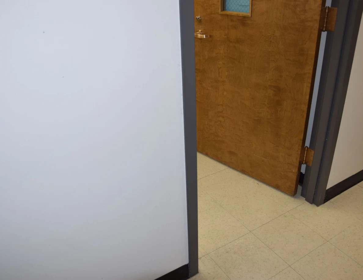 Lower office doorway with an open wooden door and pale floor tiles.