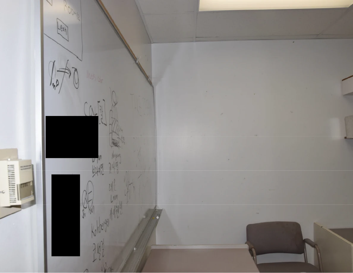 Upper office wall and whiteboard with handwriting and black redactions.