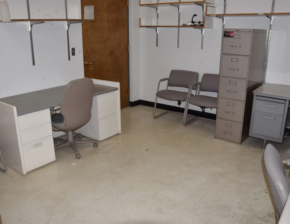 Office floor between desks, chairs and filing cabinets.