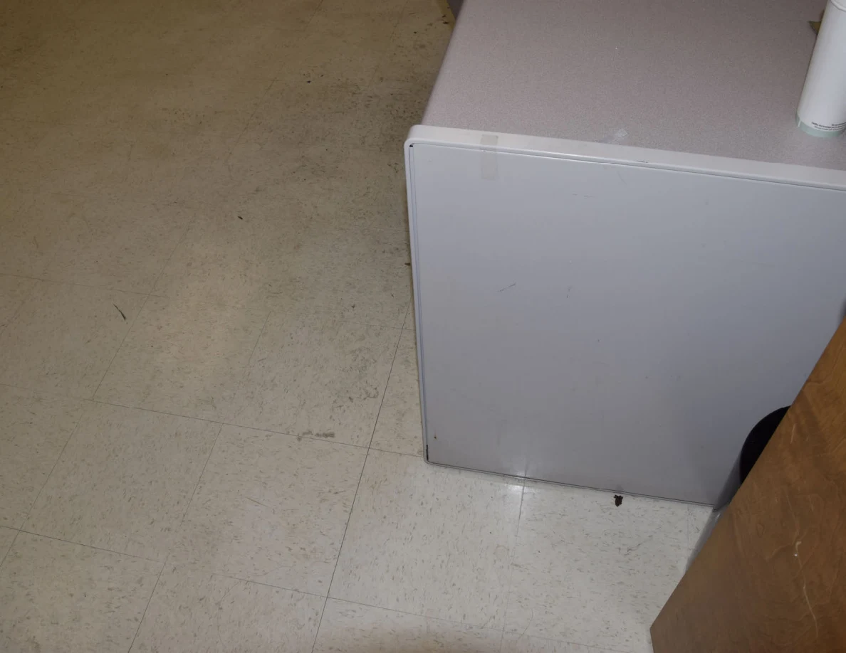 Lower corner of an office desk beside pale floor tiles.
