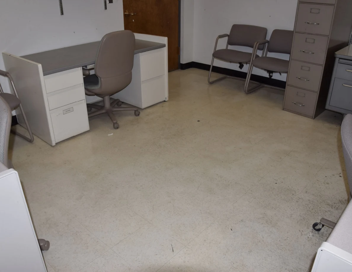 Office desks, rolling chair and two visitor chairs beside a tall filing cabinet.