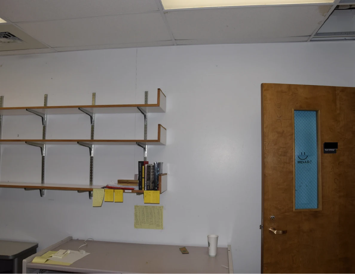 Office shelves with books and yellow notes beside a wooden door.