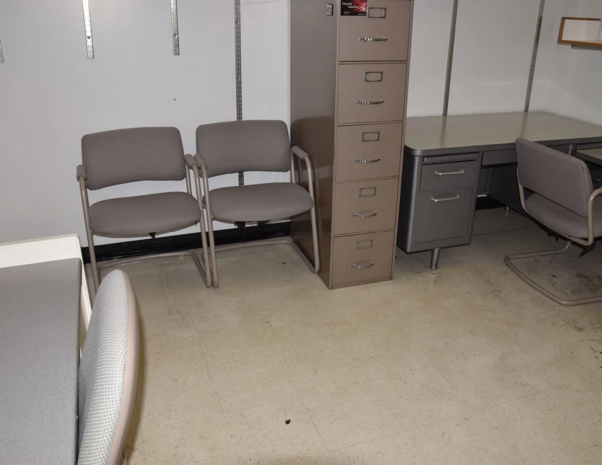 Two visitor chairs beside a tall filing cabinet and corner desk.