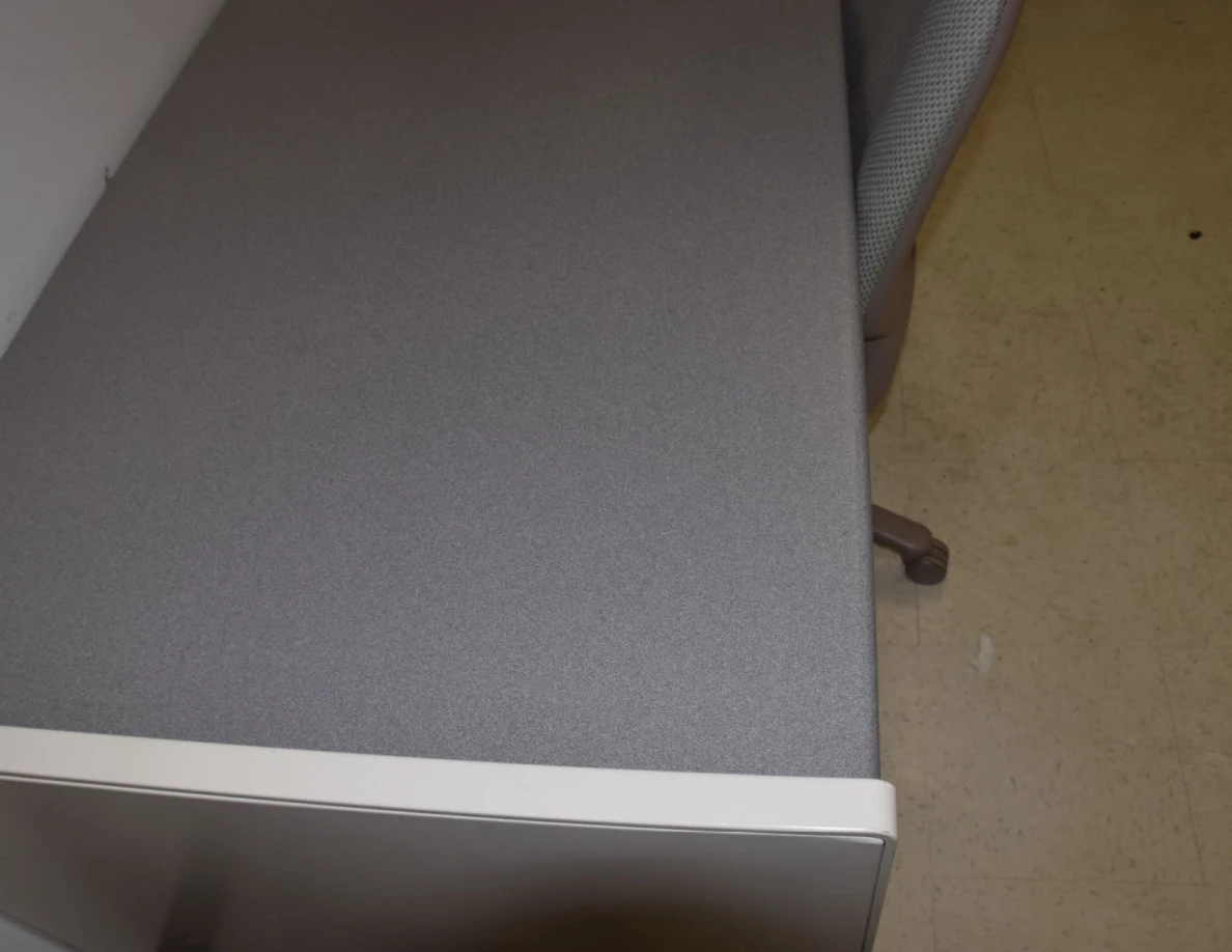 Close view of an empty gray desktop beside an upholstered chair.