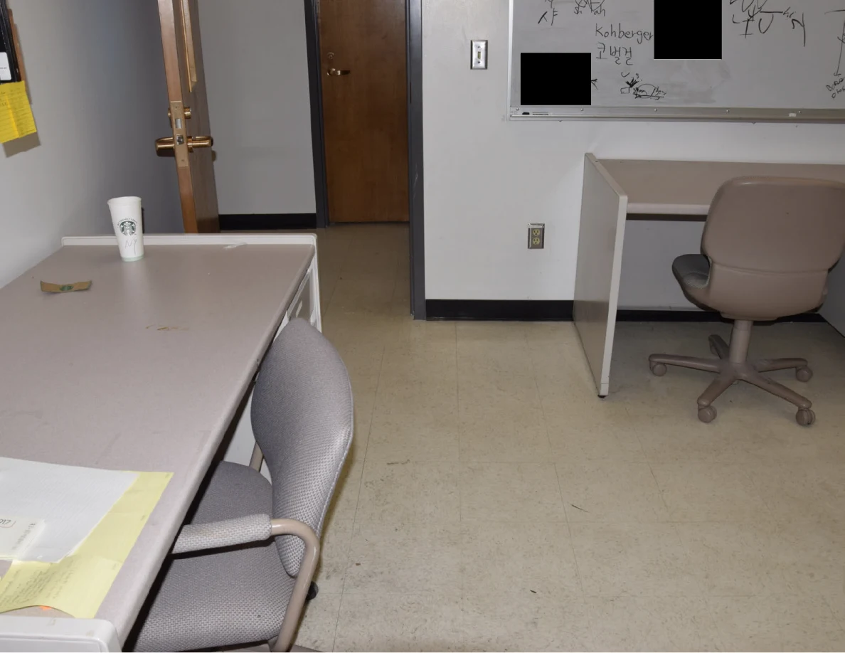 Office desks with a white cup and chairs beside an open doorway.