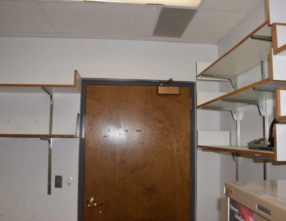 Closed wooden office door surrounded by empty wall shelves.