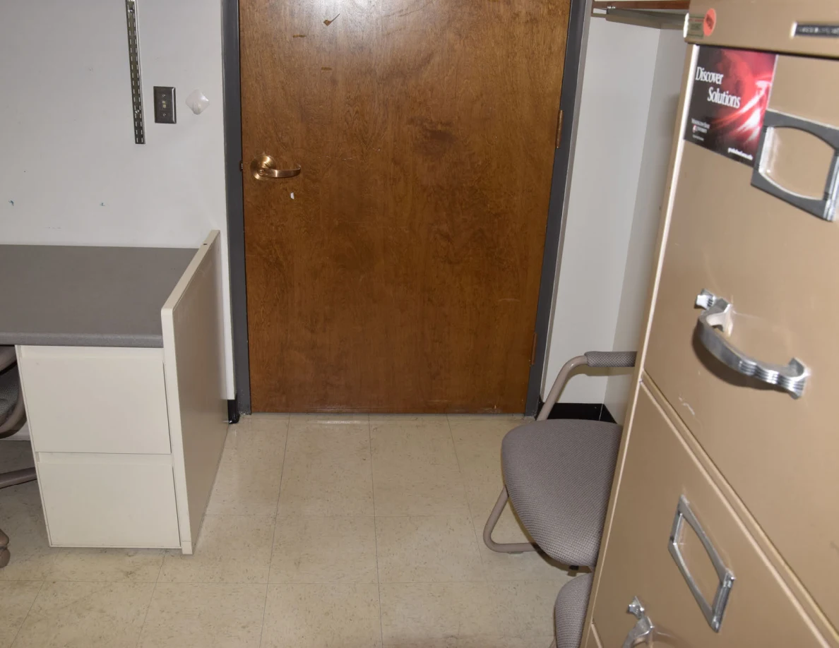 Lower wooden door beside a desk, chair and tall filing cabinet.