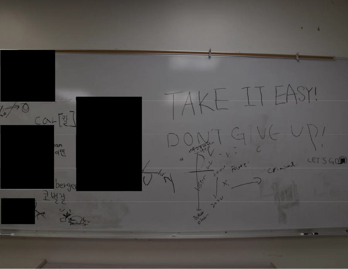 Close view of a whiteboard with handwritten messages and several black redactions.