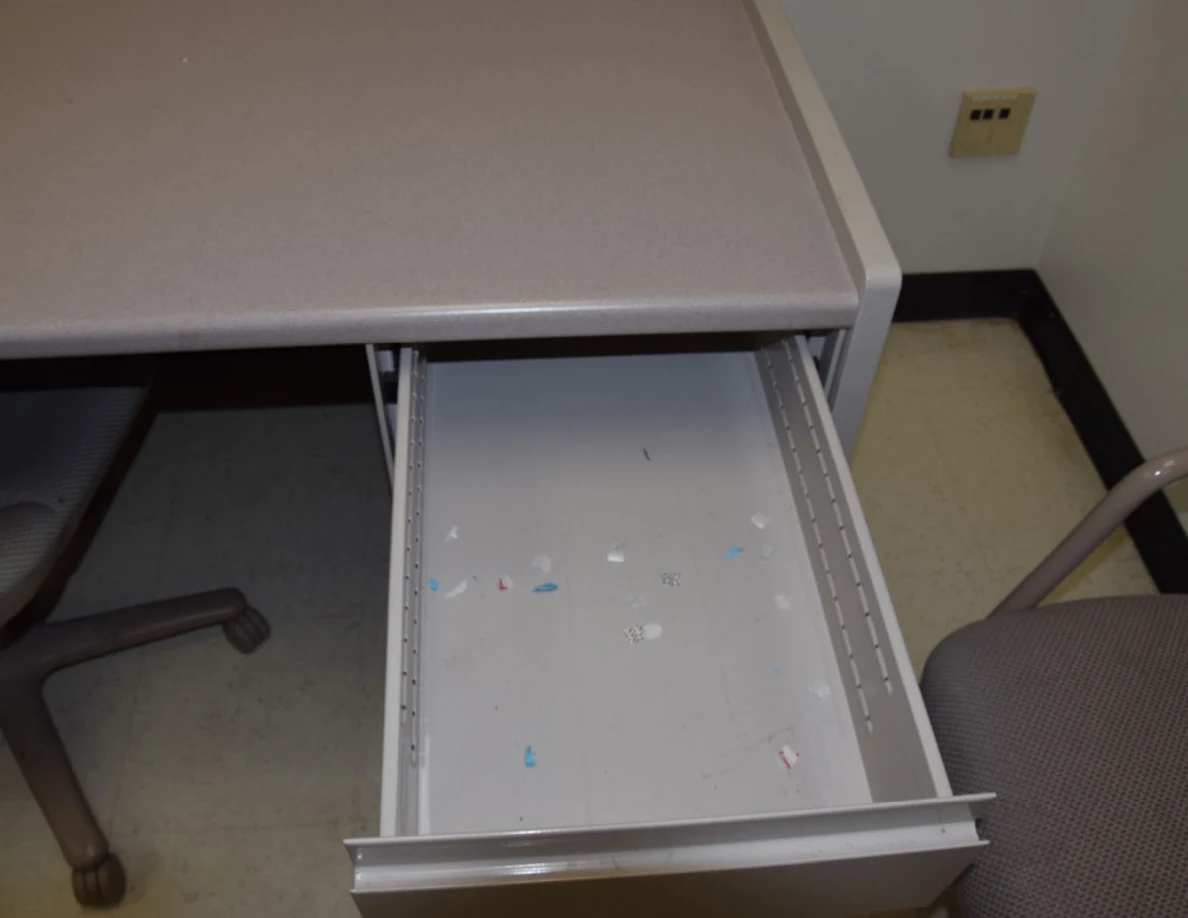 Closer illuminated view of an open drawer with small colored paper scraps.