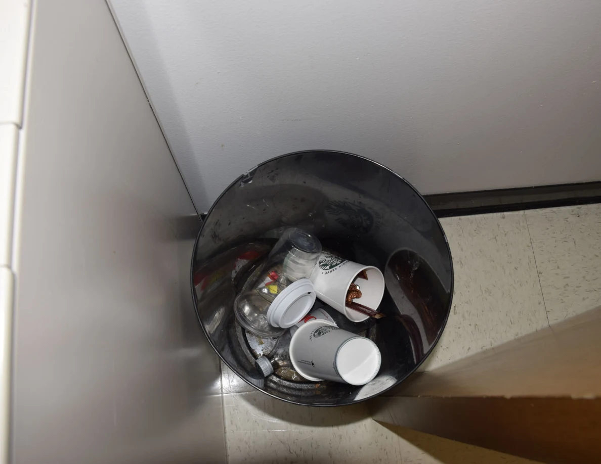 Wastebasket containing disposable cups, lids and other rubbish.