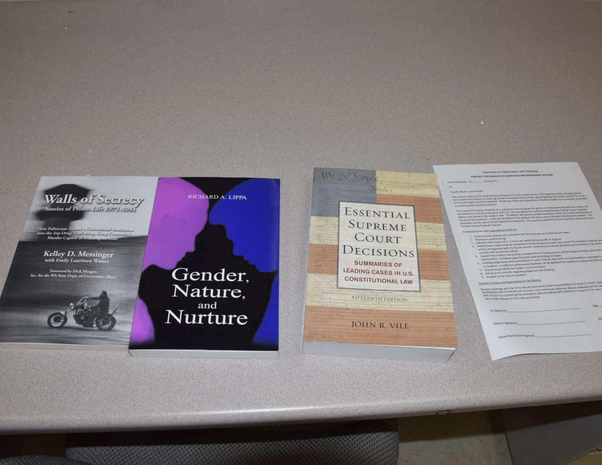 Three books and a printed sheet arranged on an office desktop.