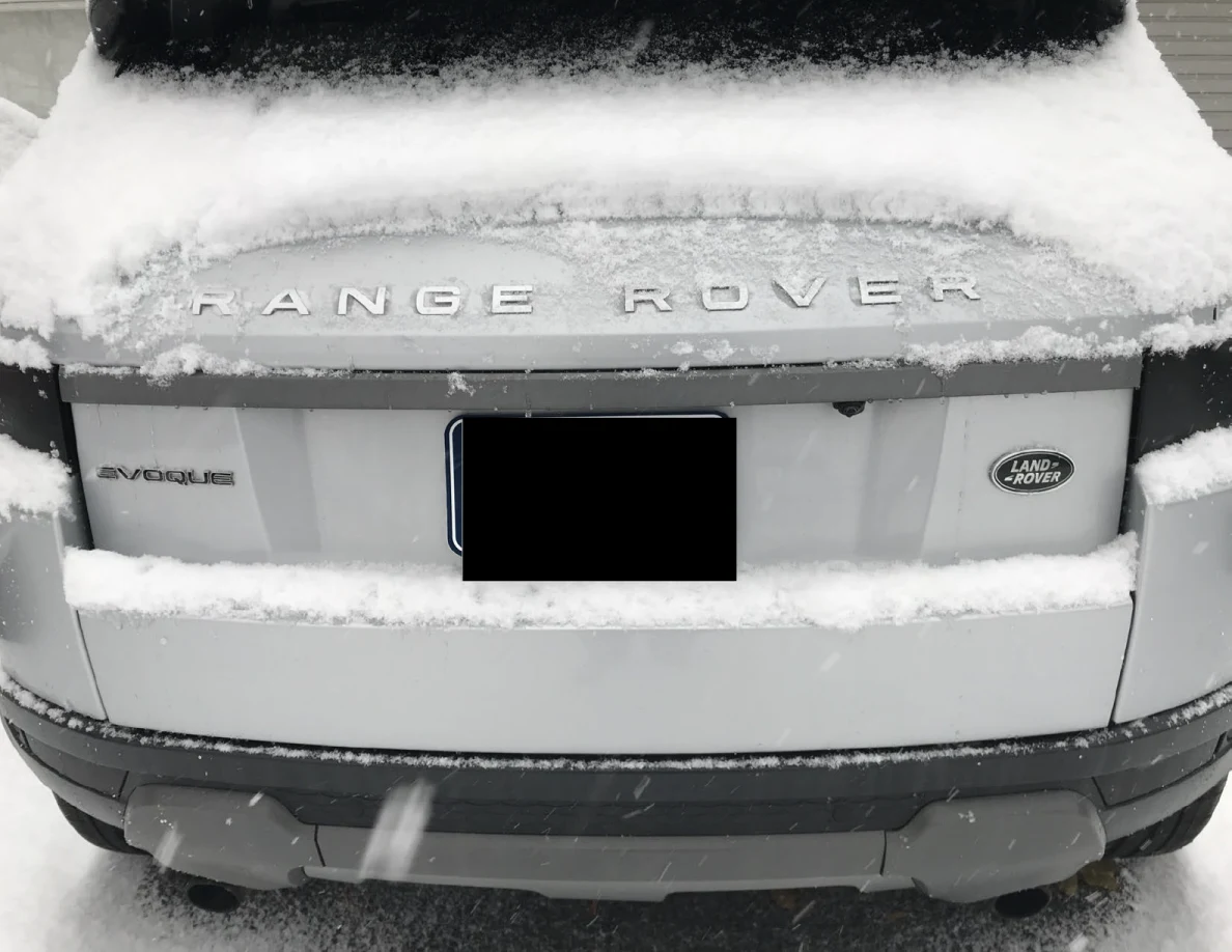 Snow-covered rear of a white Range Rover Evoque with a blacked-out license plate.