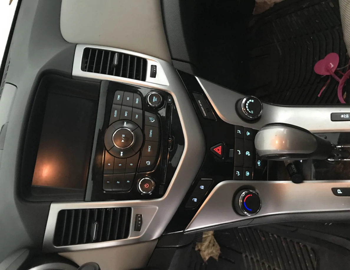 Vehicle center console with display, climate controls and automatic gear lever, photographed sideways.