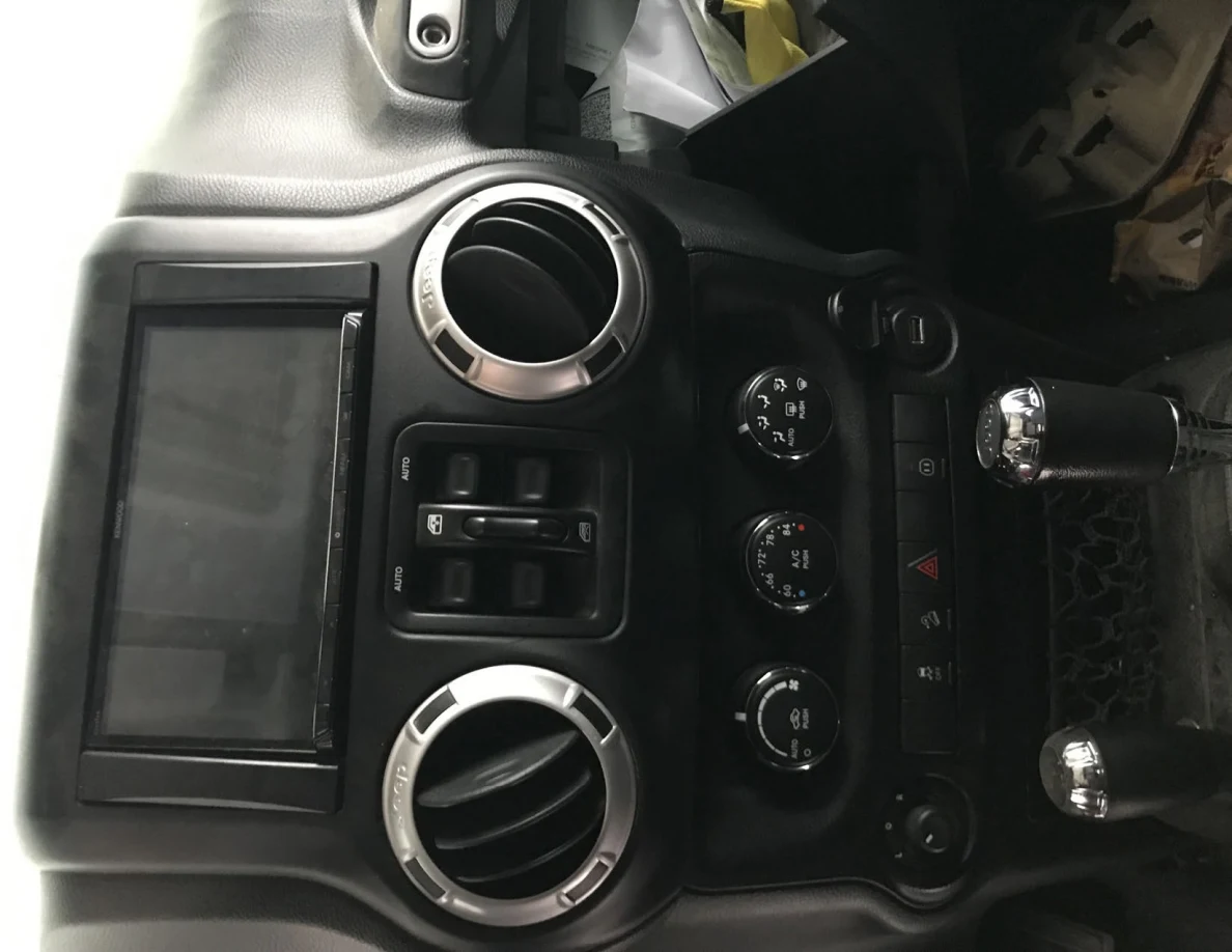 Jeep interior center console with circular vents, touchscreen and two gear levers.