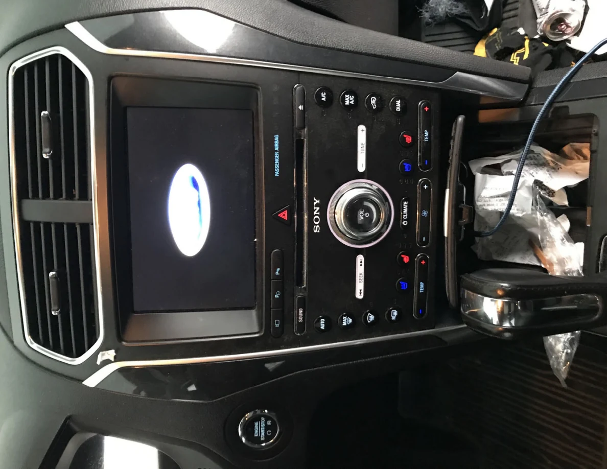 Vehicle center console with Ford logo on touchscreen, Sony controls and gear lever, photographed sideways.