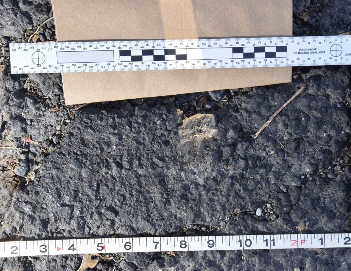 Brown envelope and two measuring scales beside a textured asphalt patch.