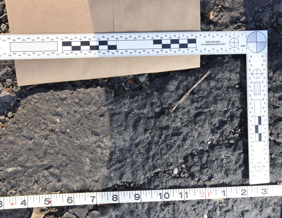 Sunlit textured asphalt within a measurement frame, with a shadow along one side.