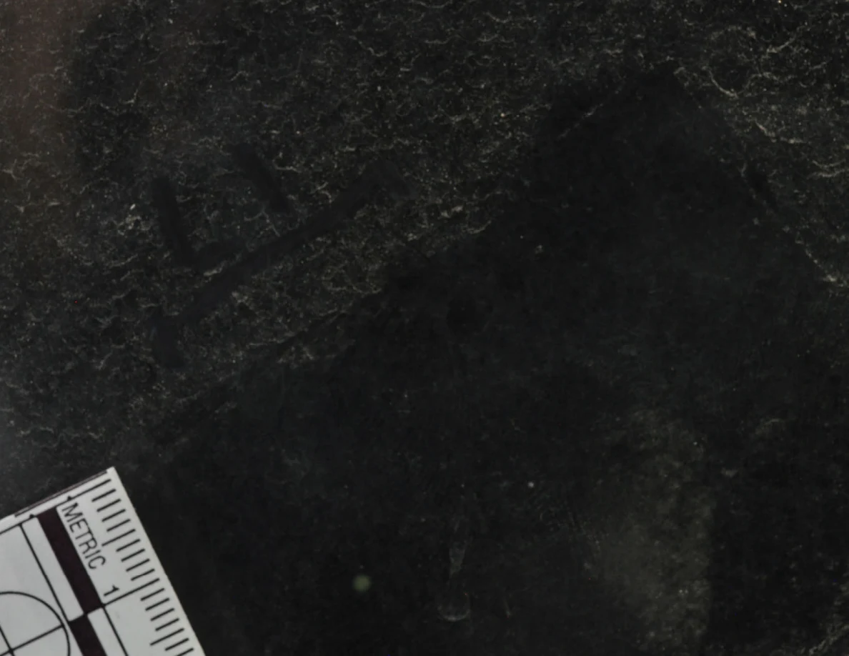 Close view of marked dark glass beside a metric scale.