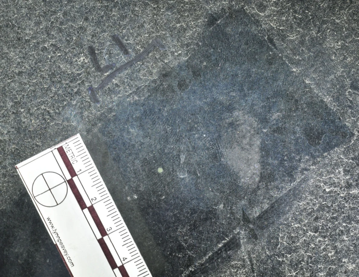 Illuminated glass with an arrow-shaped marker, a pale dot and a metric scale.