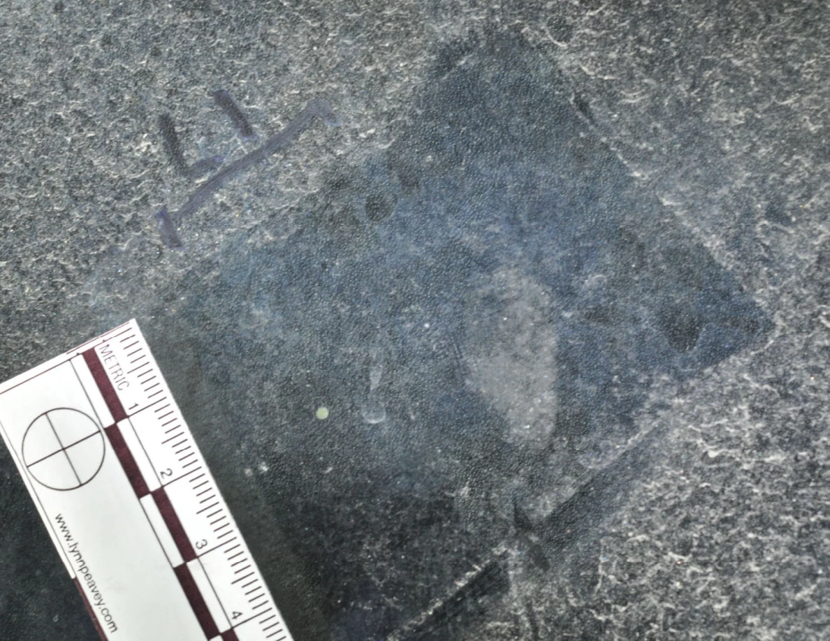 Illuminated glass with an arrow-shaped marker, a pale dot and a metric scale.