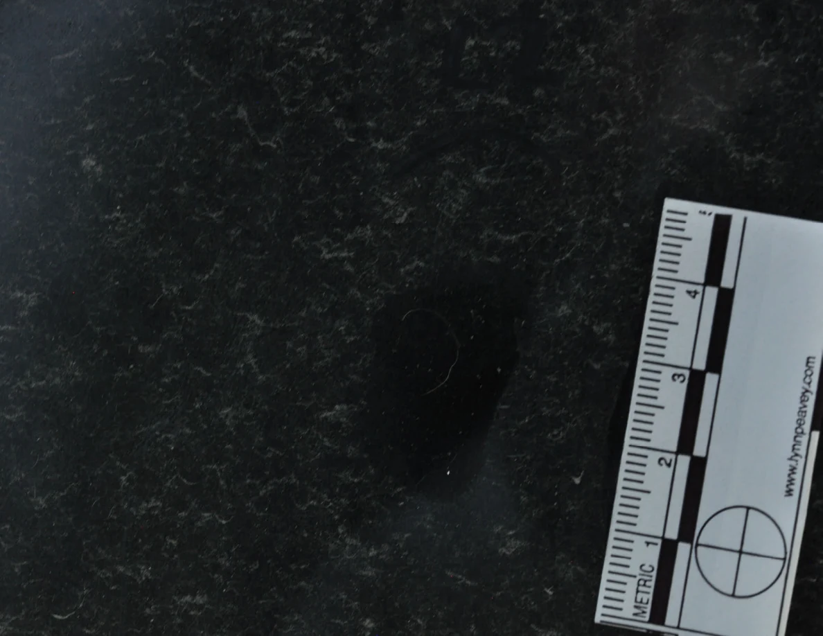 Dark glass close-up beside a vertical metric scale.