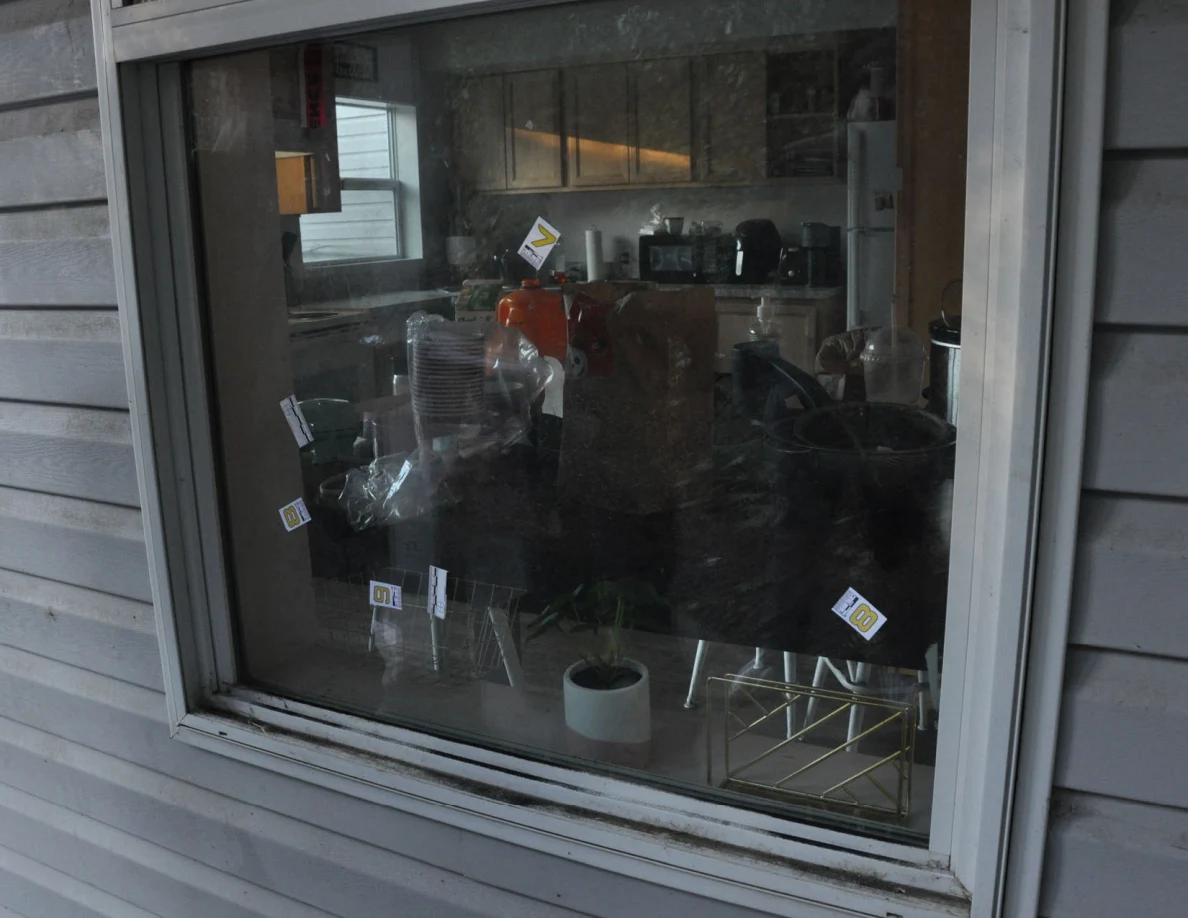 Exterior window with small numbered labels and scales; a kitchen counter and potted plant are visible inside.