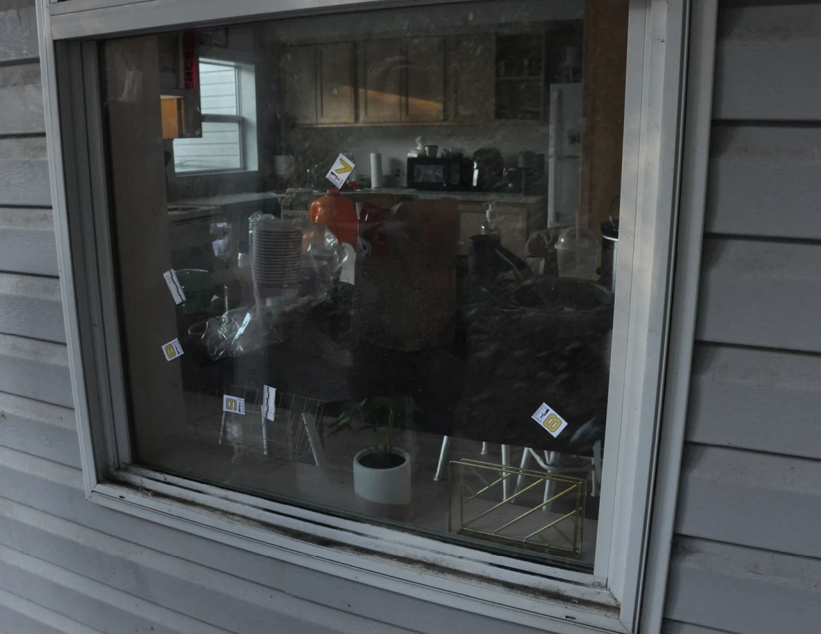 Exterior window with small numbered labels and scales; a kitchen counter and potted plant are visible inside.