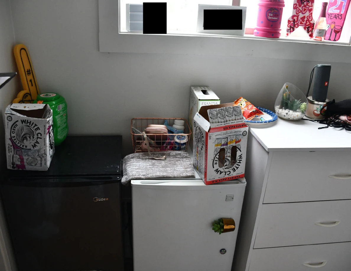 Black and white compact refrigerators beside a white drawer unit, with drink boxes, a wire basket and decorations on top.