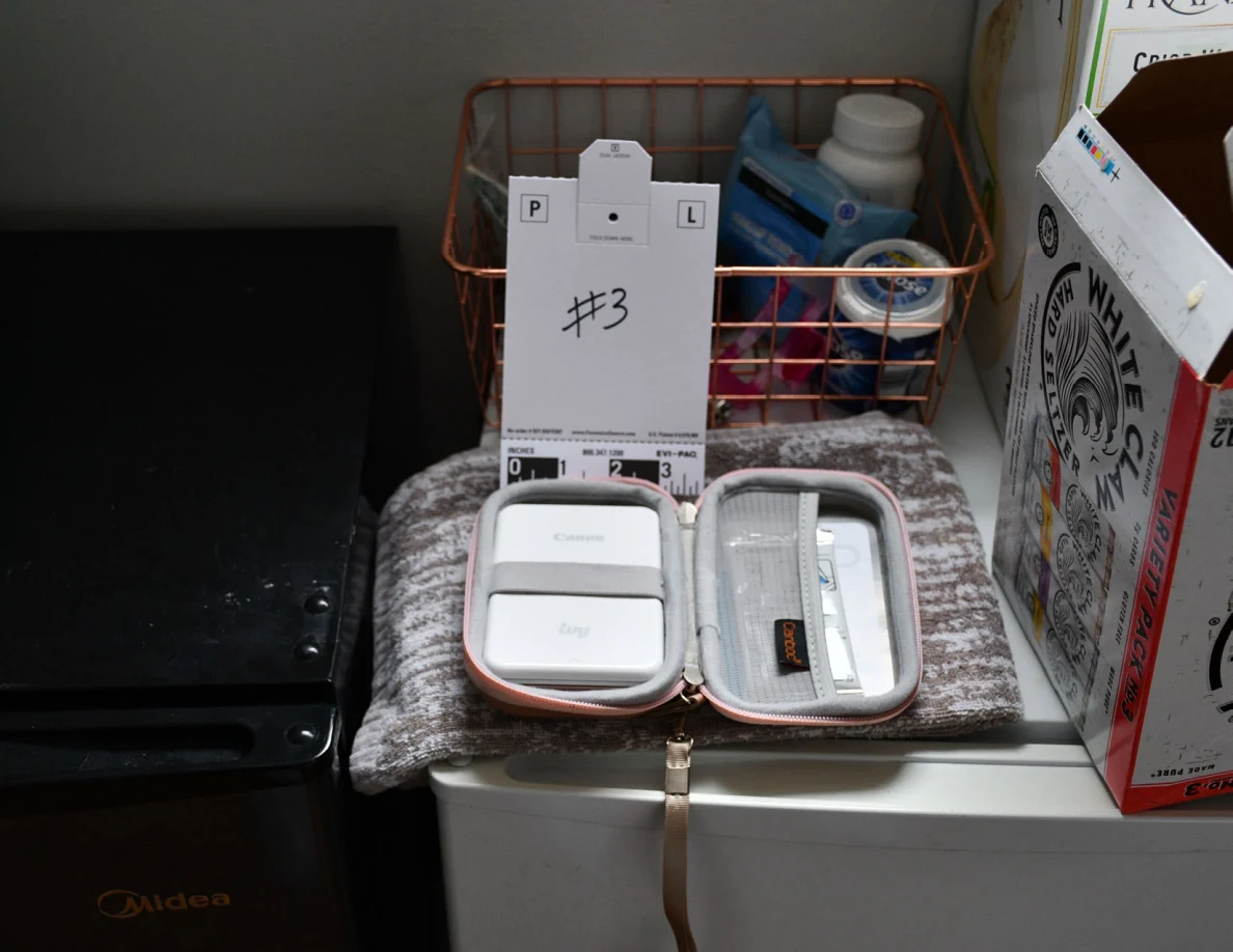 Open pink case with small white rectangular items beside a numbered 3 card and ruler.