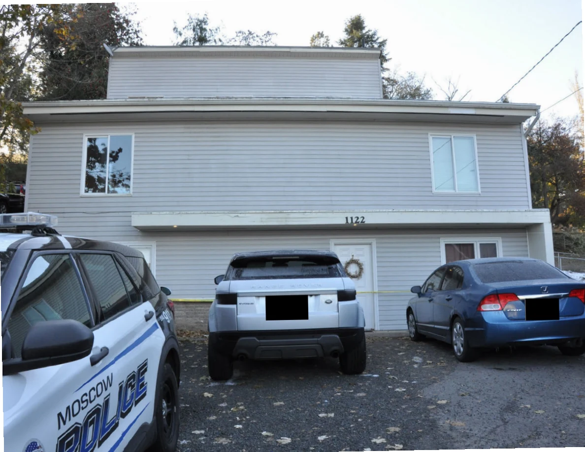 Gray-sided house with several parked vehicles, including a marked police vehicle; license plates are redacted.