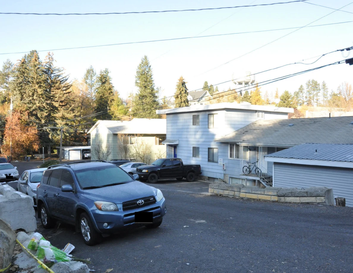 Blue SUV parked on a sloping residential street with buildings and overhead wires.