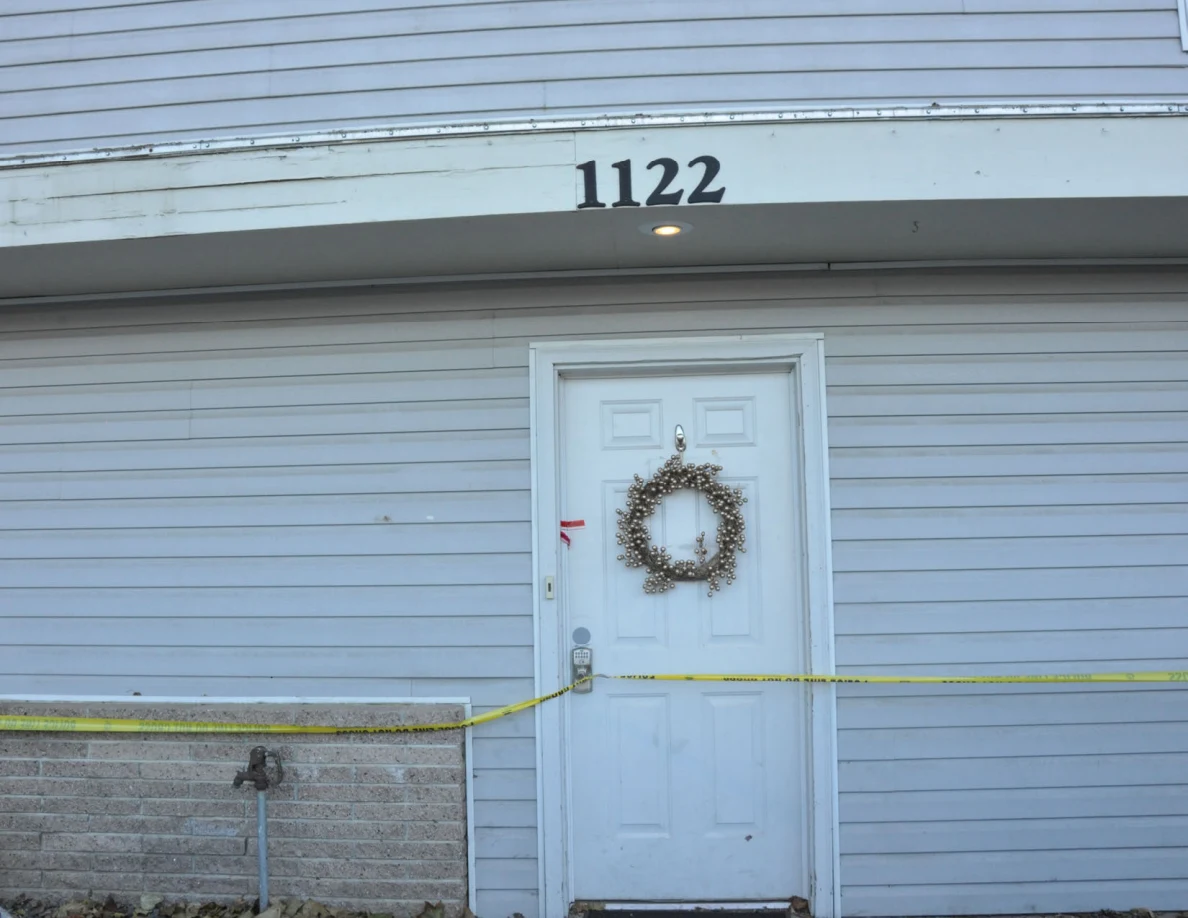 House number 1122 above a white front door with a wreath and yellow tape.