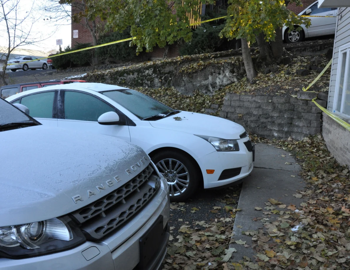 Silver Range Rover and white sedan parked below a retaining wall and yellow tape.