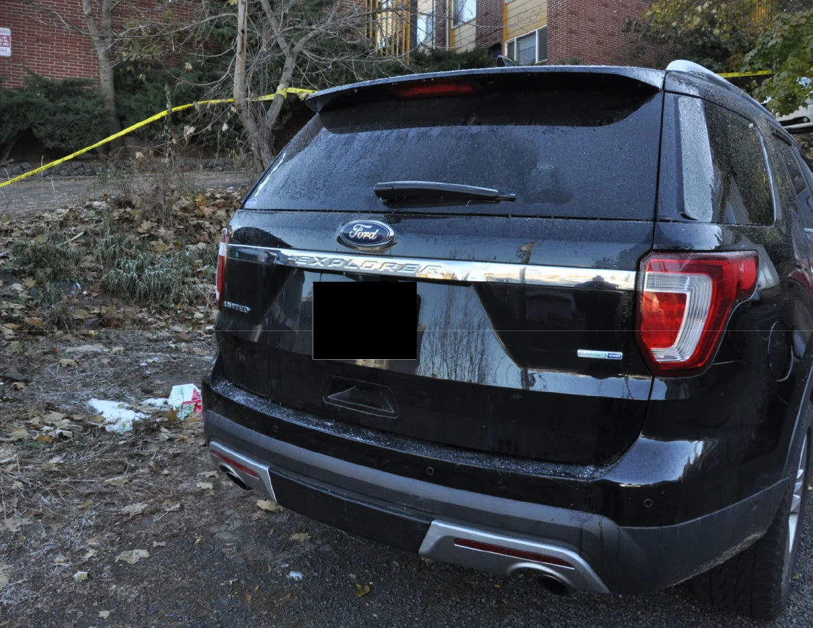 Rear of a black Ford Explorer with a redacted license plate.