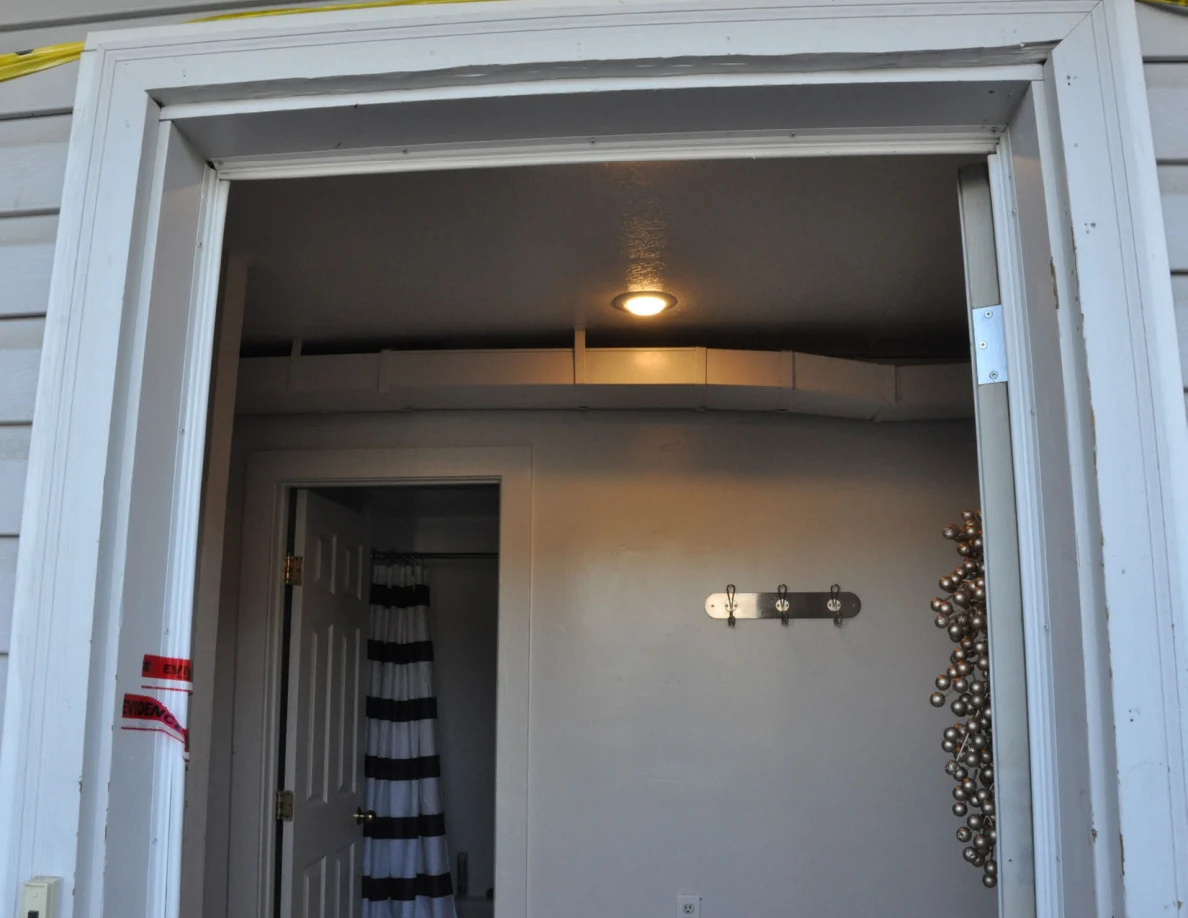 Upper front doorway framing a ceiling light, ductwork and interior coat hooks.
