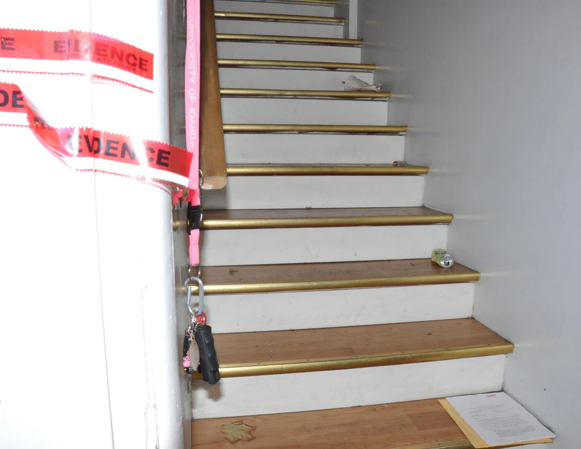 Staircase beside an entrance jamb with red evidence tape and hanging keys.