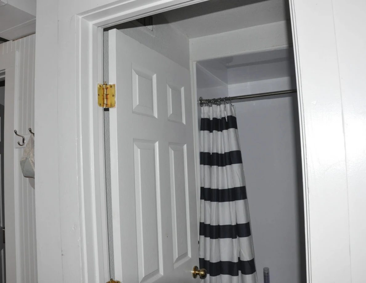 Upper bathroom doorway with an open white door and striped shower curtain.