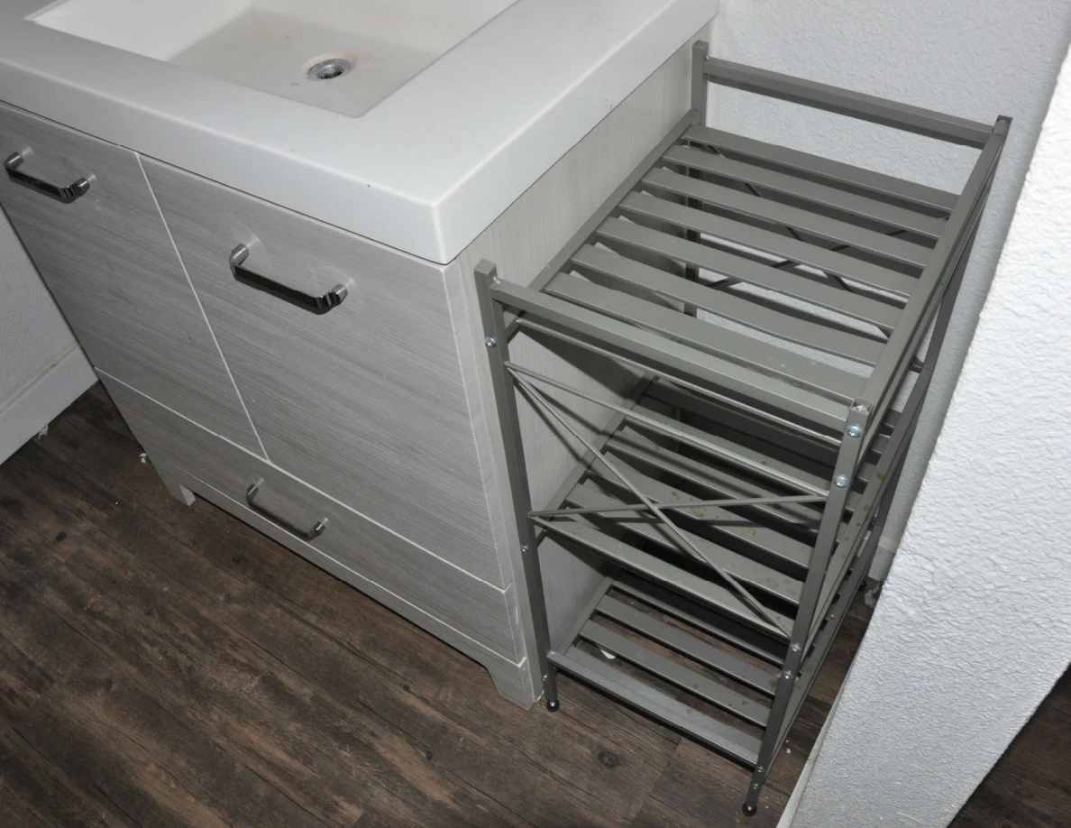 Gray bathroom vanity cabinet and empty narrow metal shelving unit.