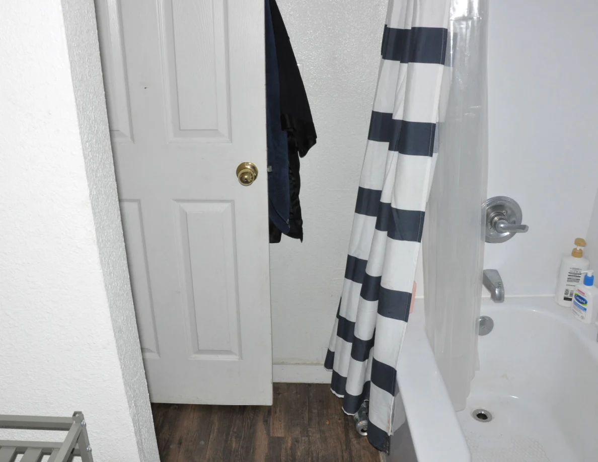 Bathtub, striped shower curtain and partly open white bathroom door.