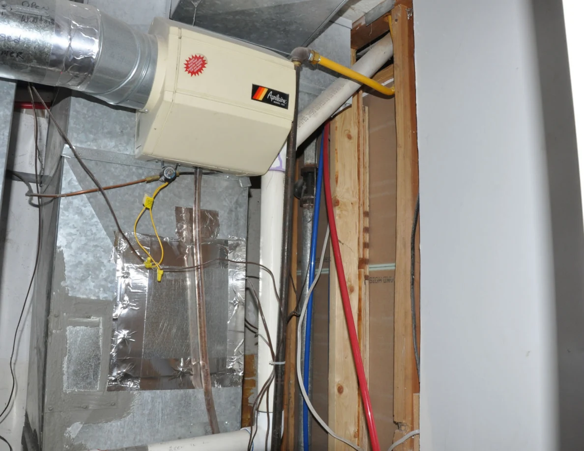 Ventilation equipment mounted beside metal ducts and exposed wood framing.