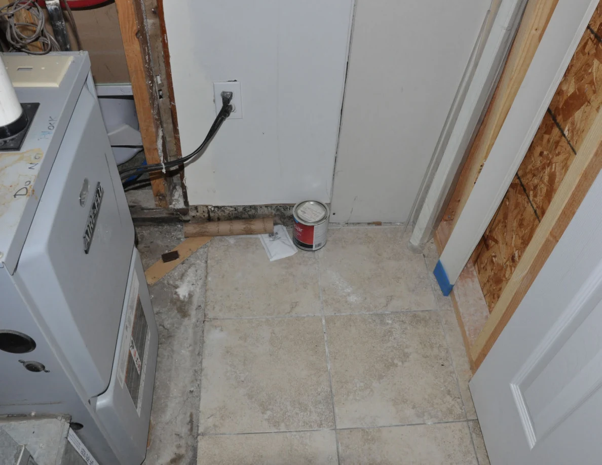 Utility-room floor with paint can, exposed cables and furnace base.