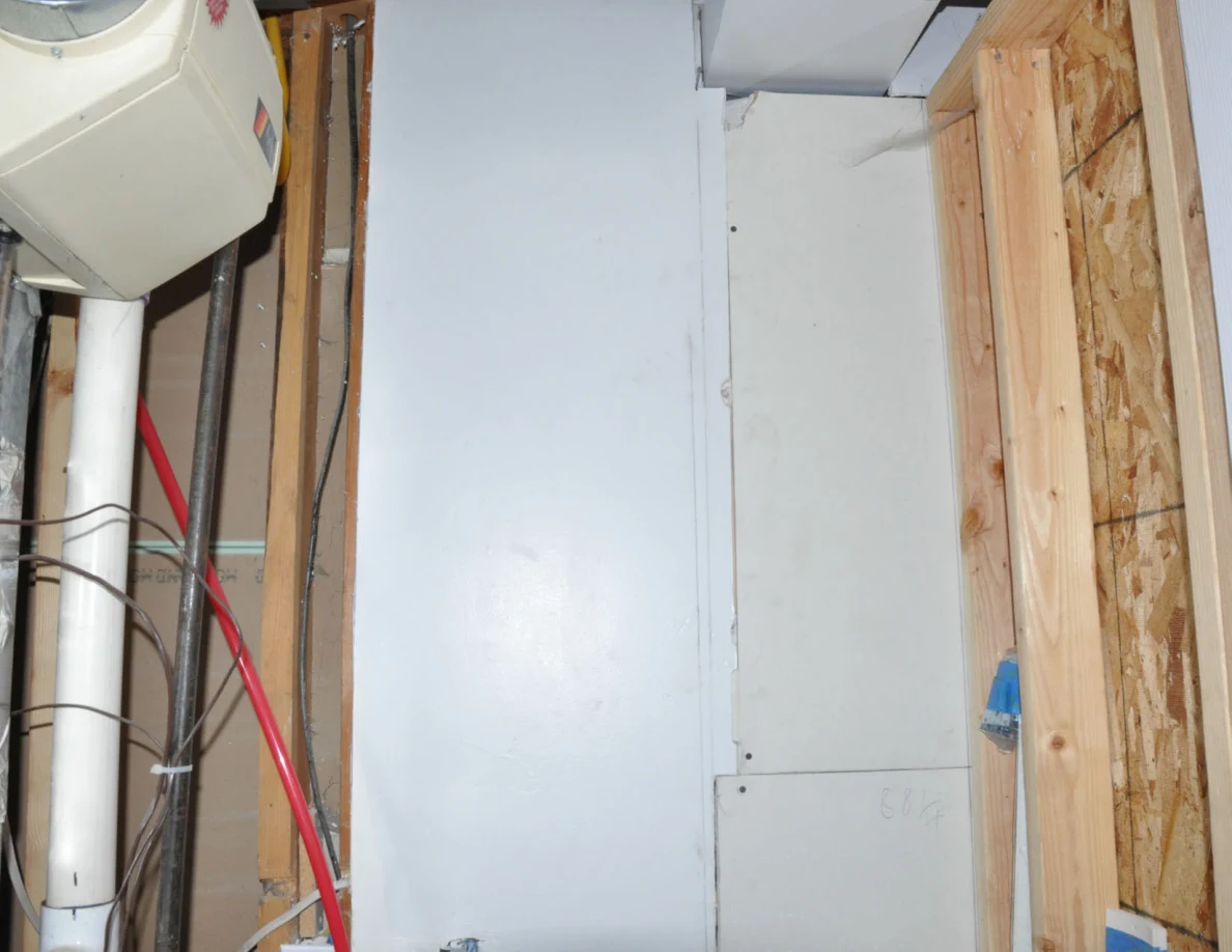 Upper utility-room wall panels, wood framing and red plumbing line.