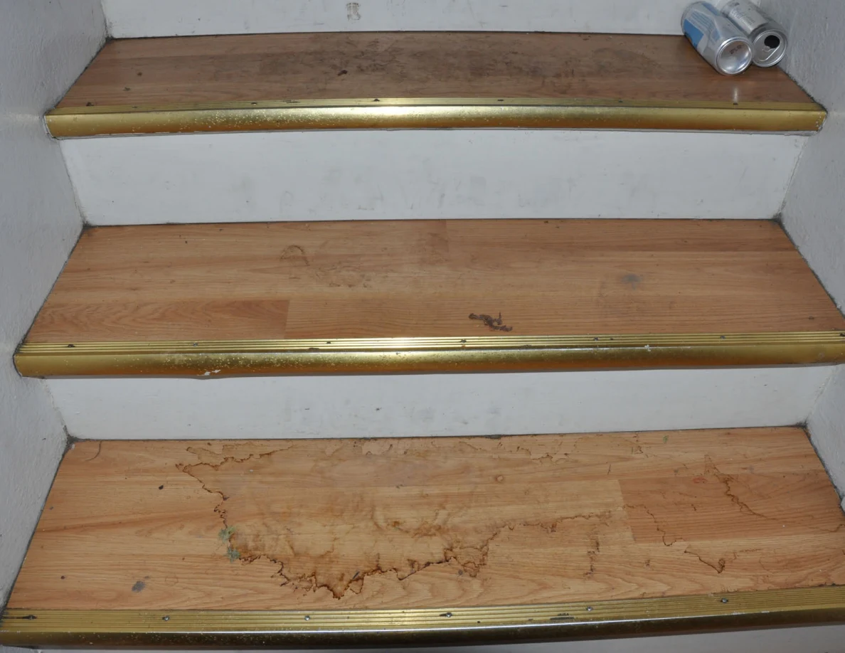 Wooden stair treads with irregular brown outlines and two cans at the upper right.