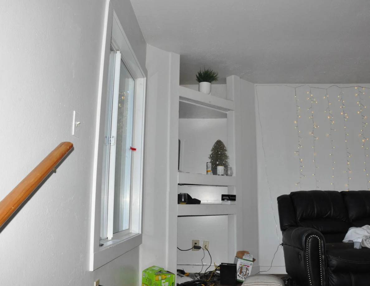 Upper stair landing with built-in shelves, a potted plant, string lights and black seating.